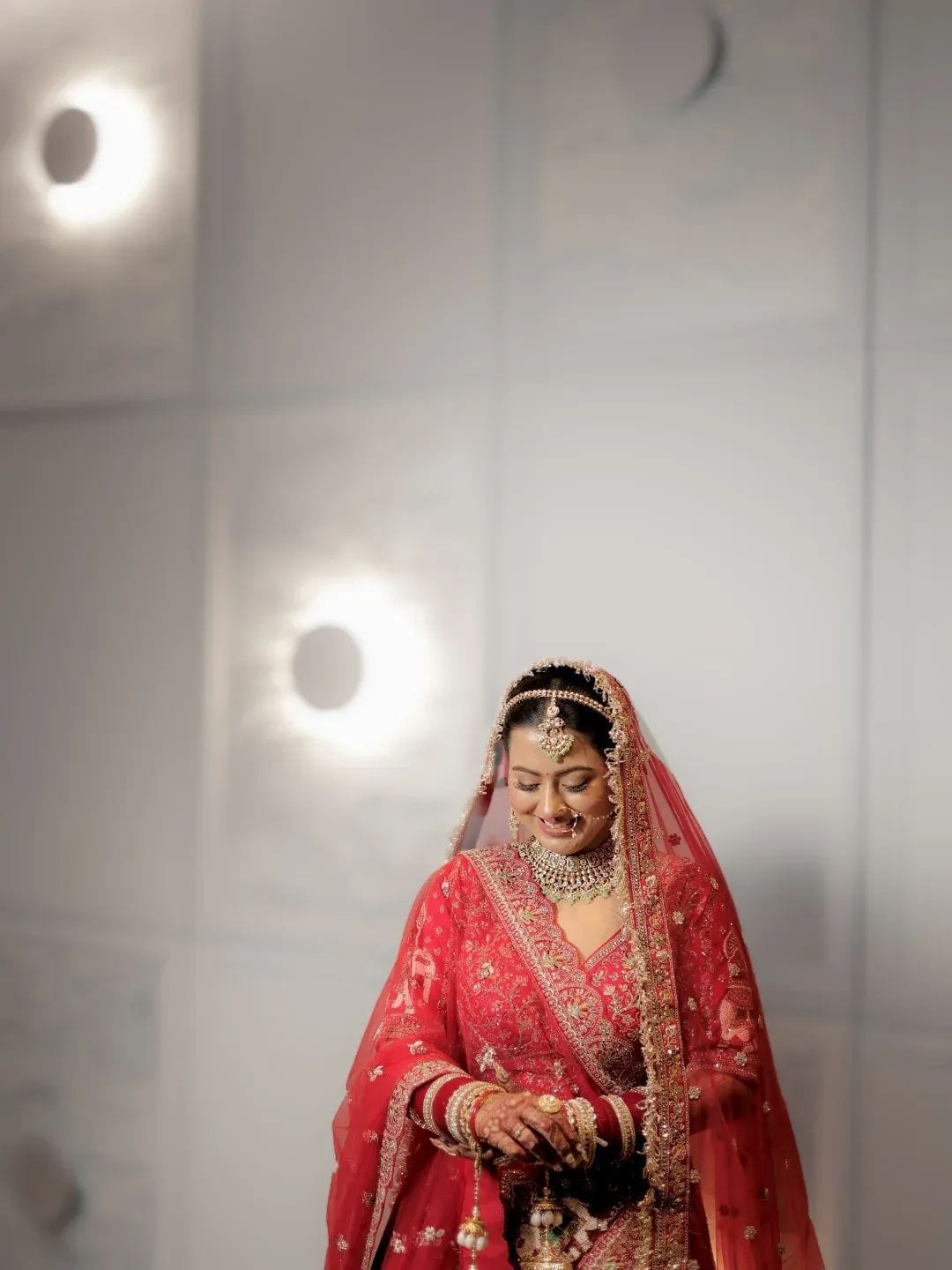 The veiled bride smiling down at her kaleere against a white panelled wall