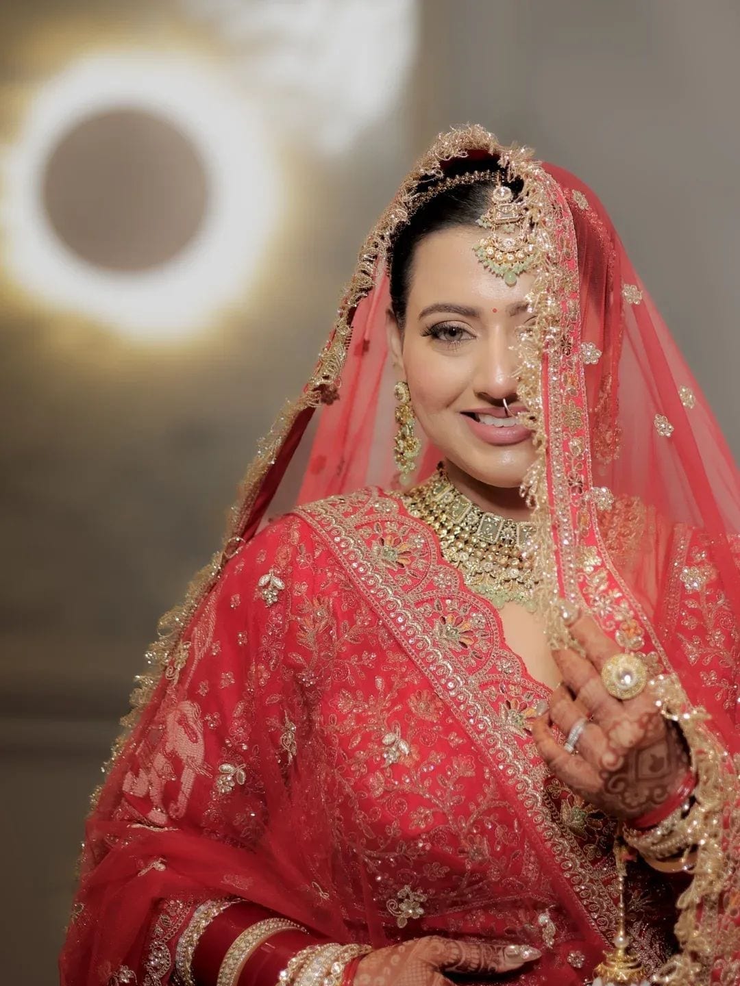 The bride laughing under her veil, gold jewellery catching the light