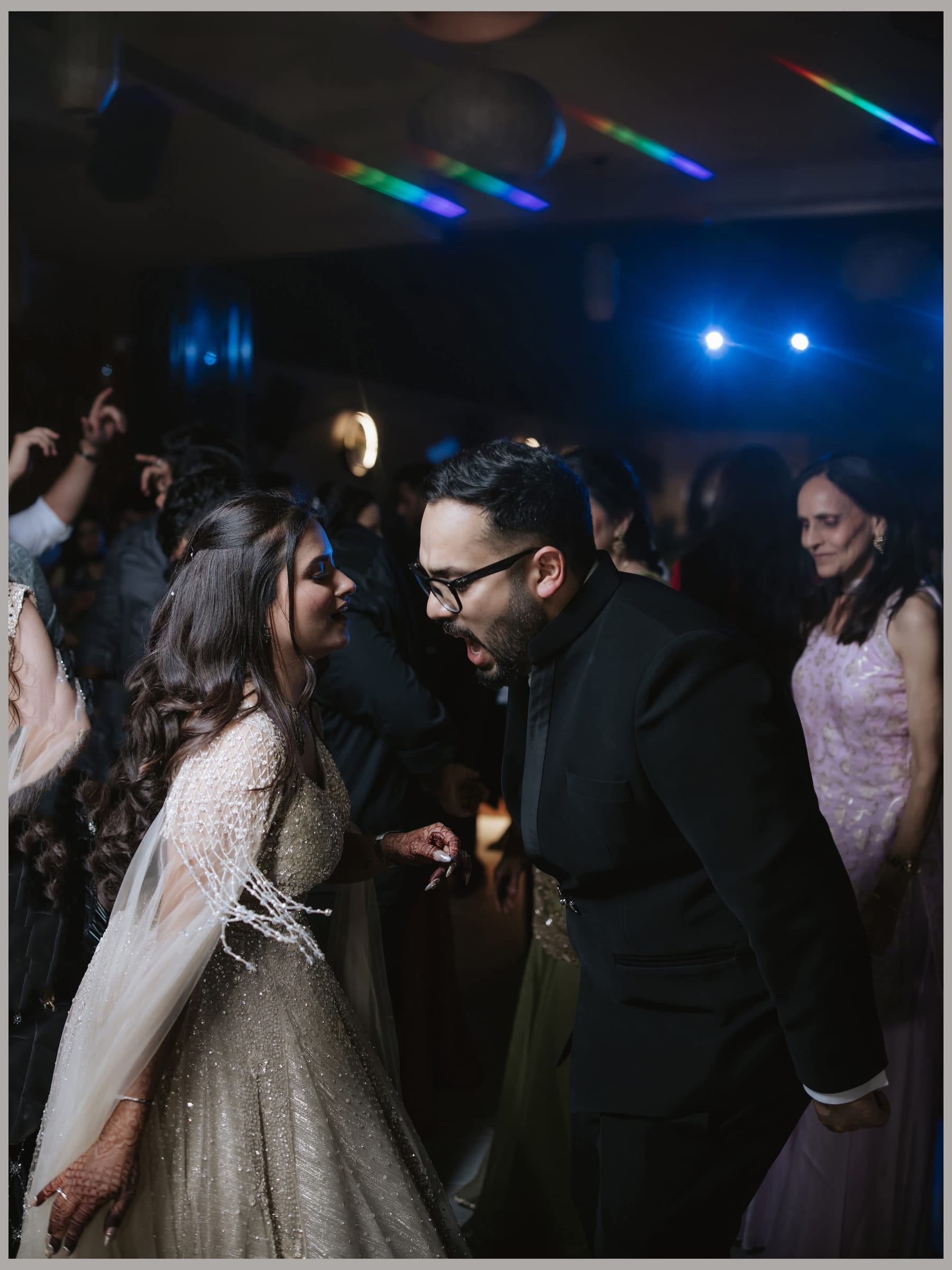 The couple dancing face to face on a crowded reception dance floor