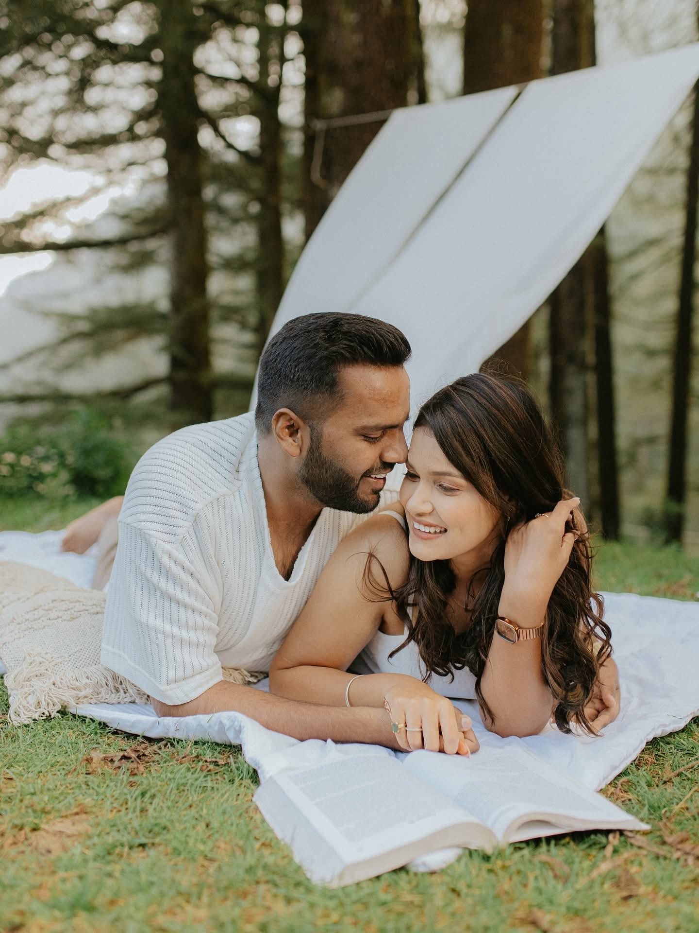The couple lying close on a blanket in the pines