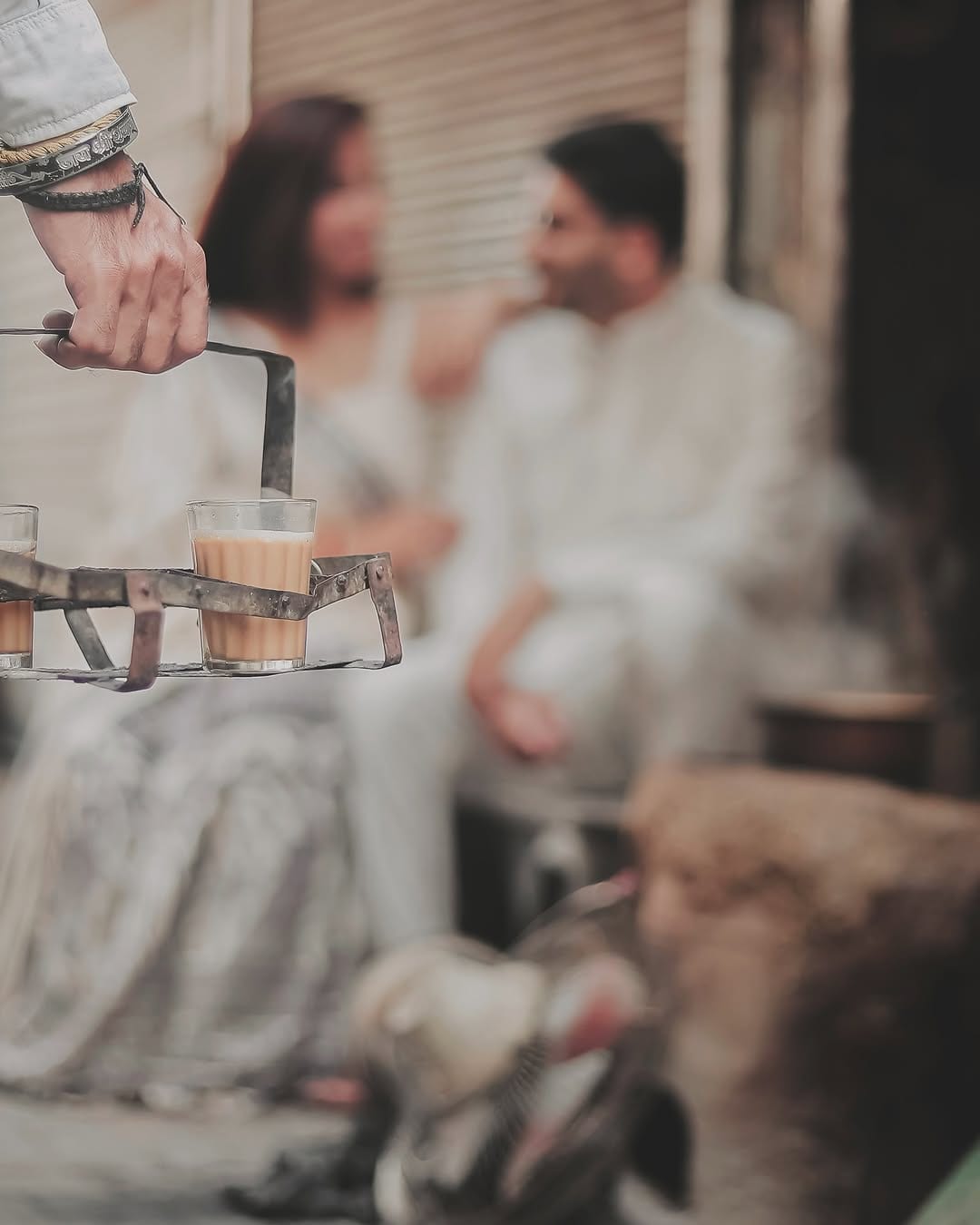 Glasses of chai in the foreground, a couple laughing softly behind
