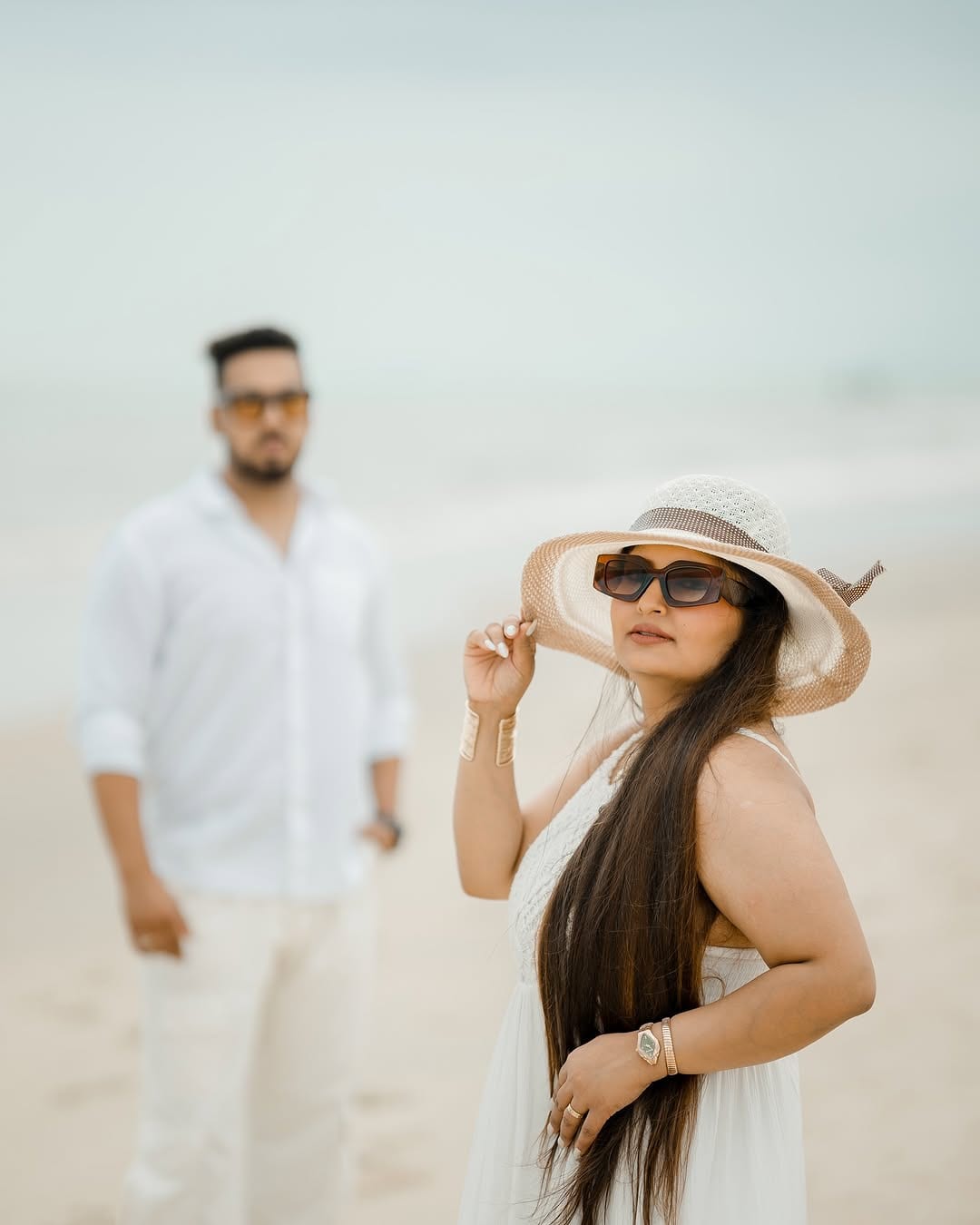 A bride-to-be holding her sun hat on a misty beach