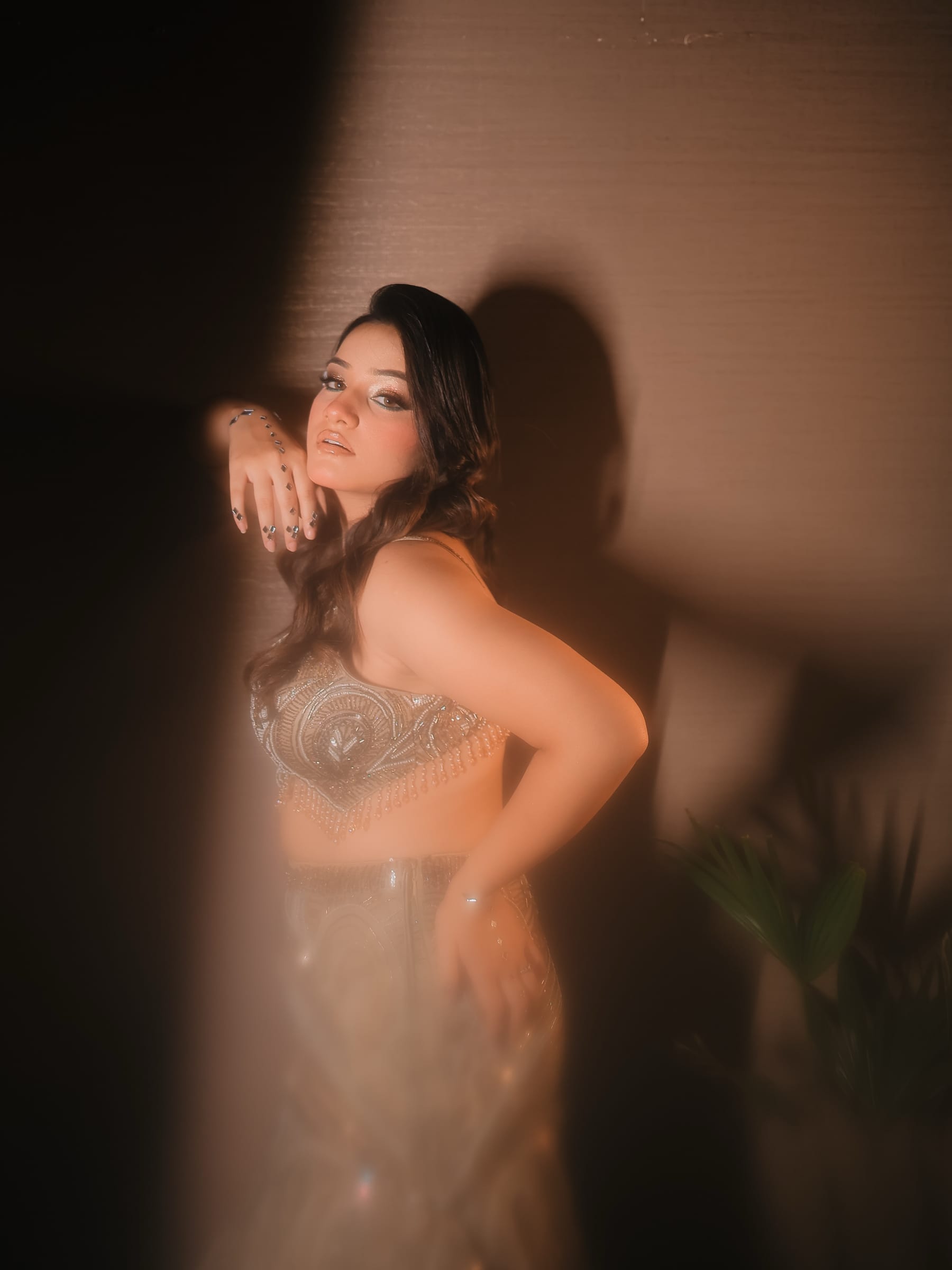 A hazy warm-toned portrait, wrist draped near the chin, shadows playing on the wall