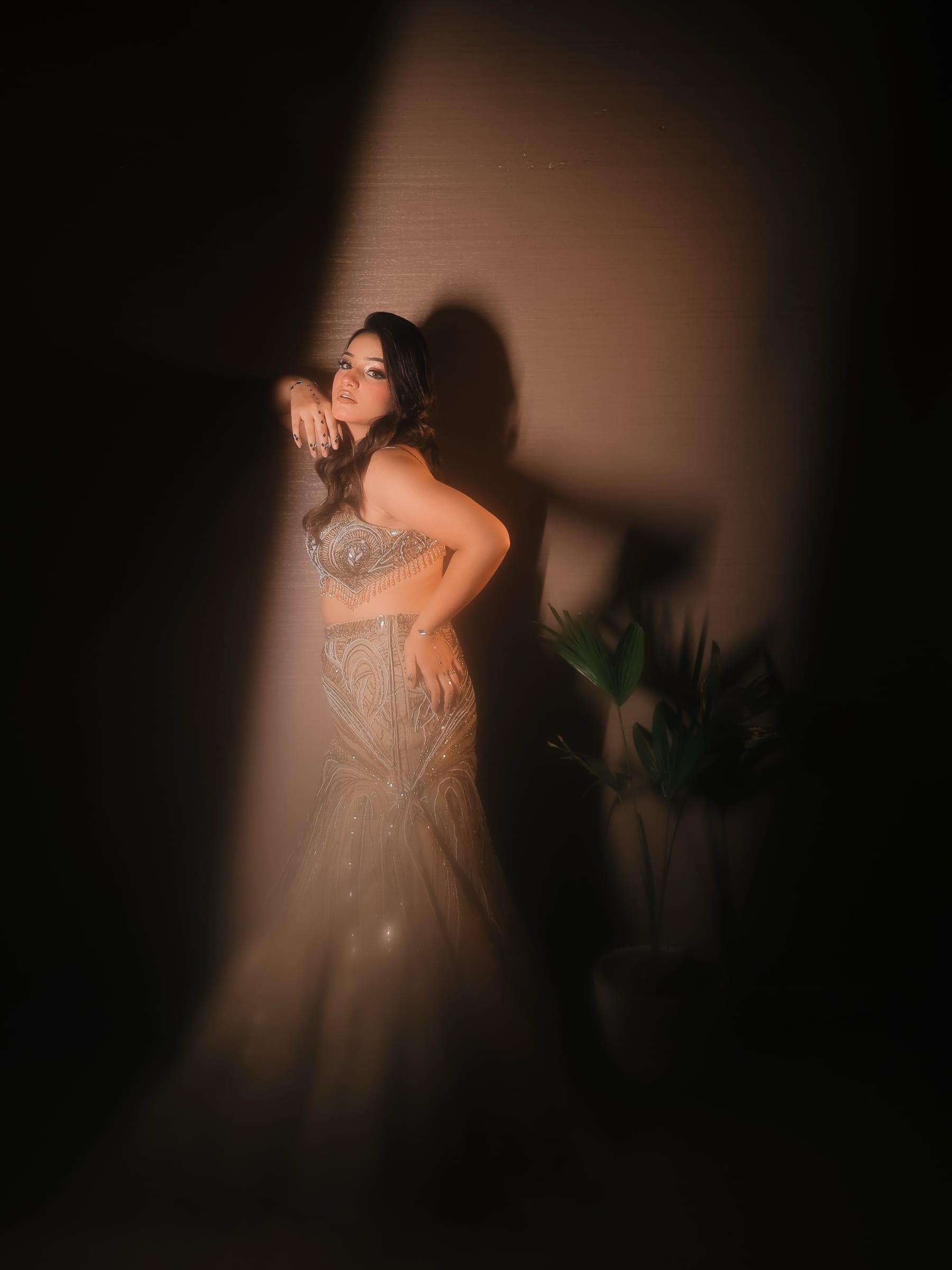 A portrait sitter leaning into a shaft of warm light against a textured wall