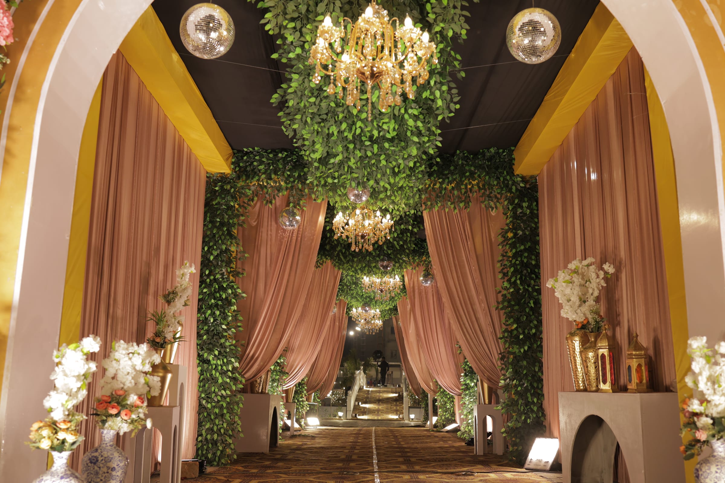 A draped stage under chandeliers and hanging greenery