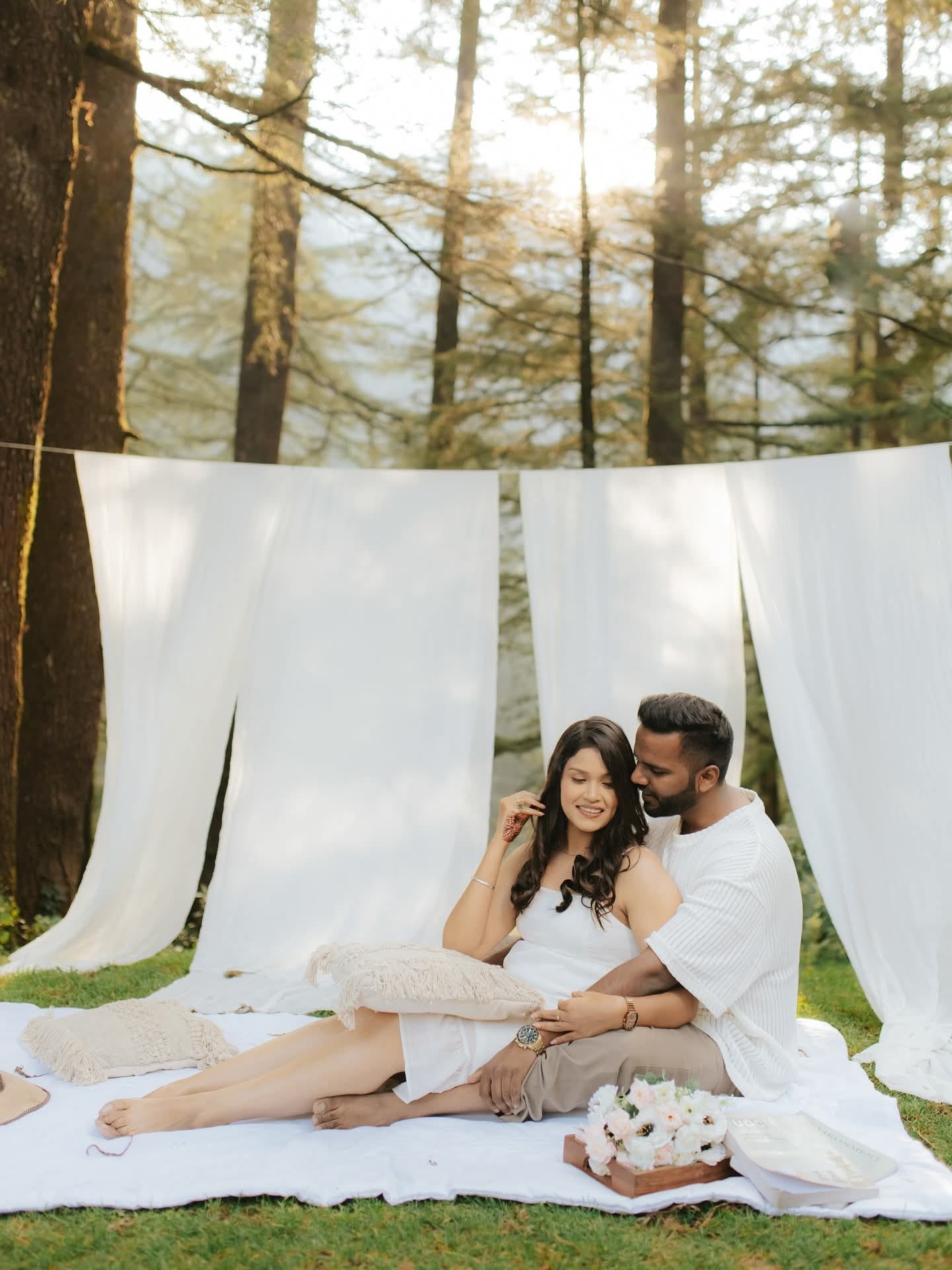 The couple among pines, white drapes hung between the trunks