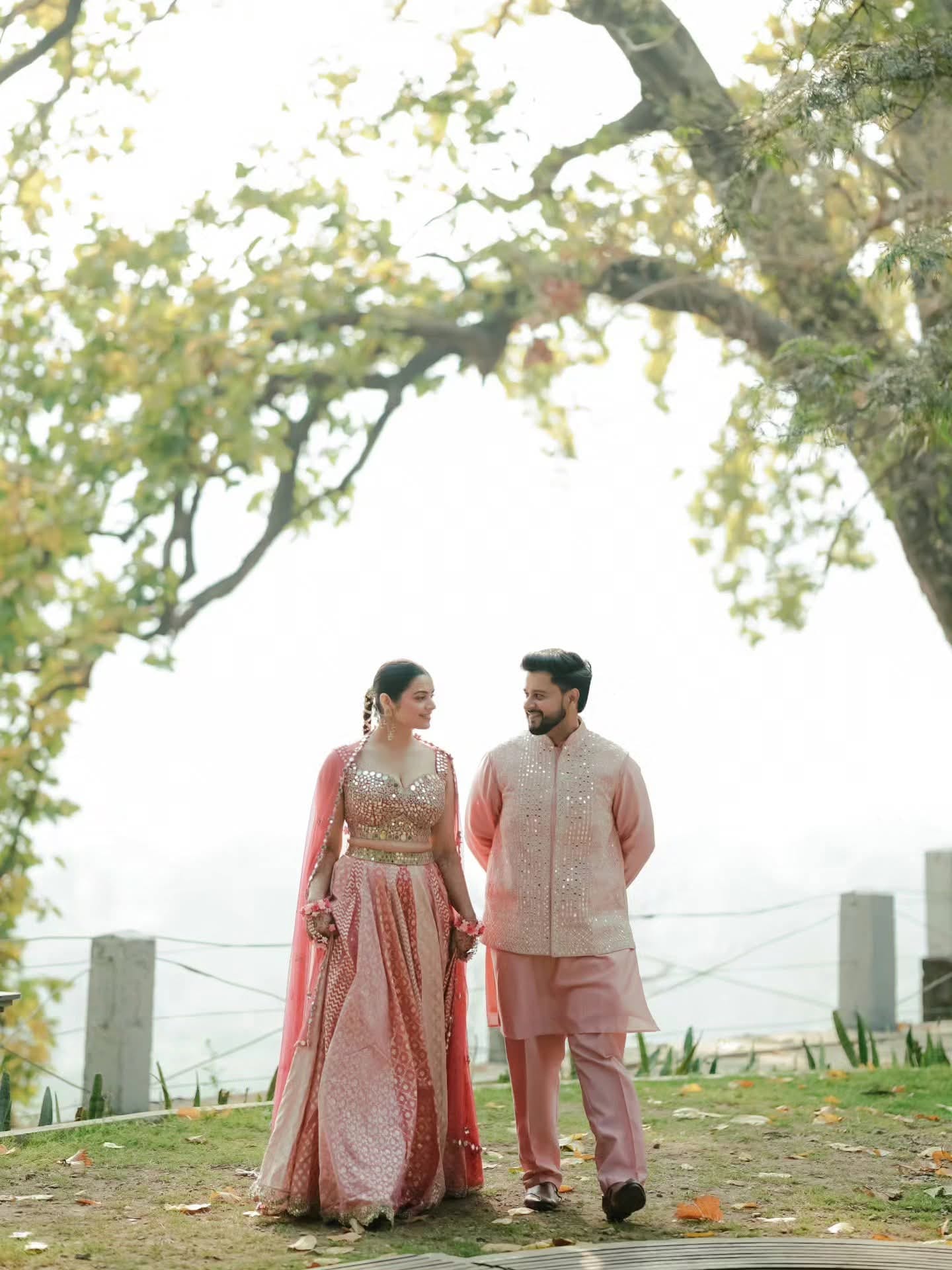 The couple in matching pink, standing in hill mist